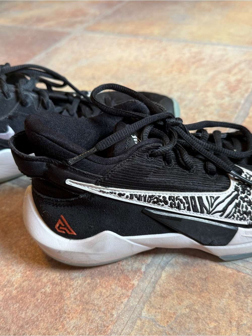 Nike Kids Black Sneakers with White Zebra Swoosh and Orange Logo